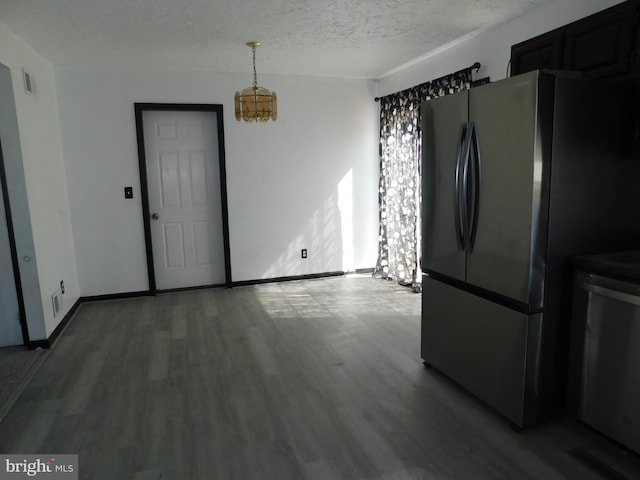 unfurnished dining area with visible vents, a textured ceiling, baseboards, and wood finished floors