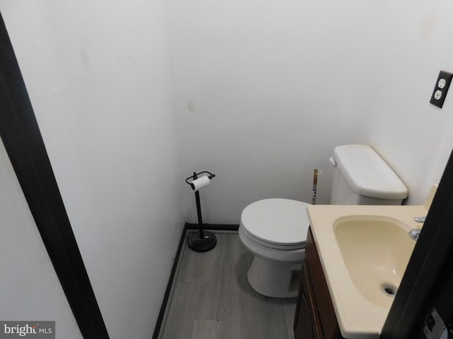 bathroom with wood finished floors, vanity, toilet, and baseboards