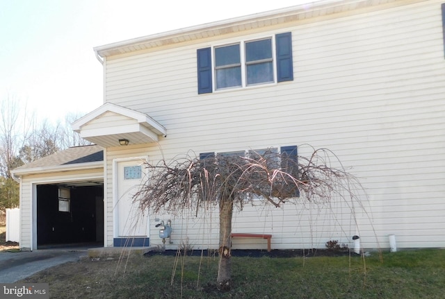 view of side of home featuring an attached garage, driveway, and roof with shingles