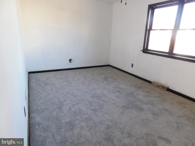 unfurnished room with carpet floors, visible vents, and baseboards