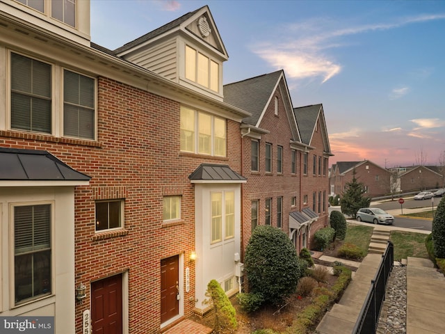 property exterior at dusk featuring brick siding