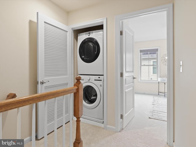 clothes washing area featuring carpet floors, laundry area, and stacked washer and dryer