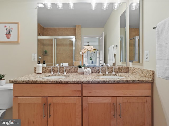 full bathroom featuring double vanity, a stall shower, toilet, and a sink