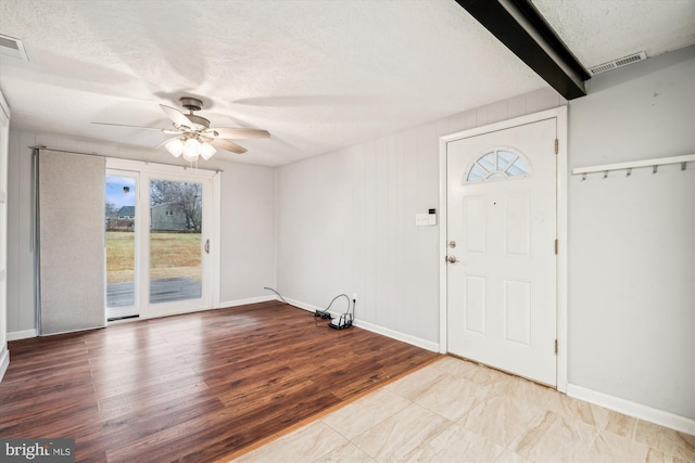 entrance foyer featuring beam ceiling, ceiling fan, a textured ceiling, and light hardwood / wood-style flooring