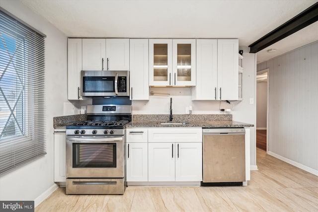 kitchen featuring stainless steel appliances, white cabinetry, and dark stone counters