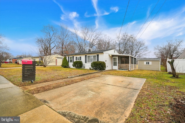 view of front of home featuring an outbuilding, a sunroom, and a front yard