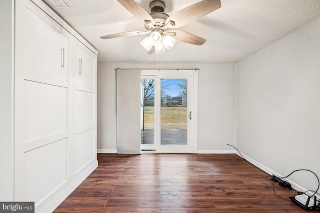 unfurnished dining area with a textured ceiling, dark hardwood / wood-style floors, and ceiling fan