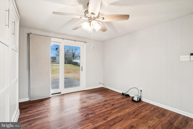 empty room with dark wood-type flooring, ceiling fan, and a textured ceiling