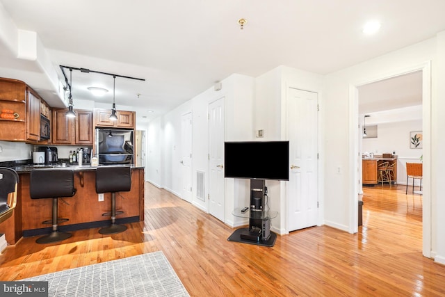 kitchen featuring a breakfast bar area, fridge, kitchen peninsula, pendant lighting, and light hardwood / wood-style floors