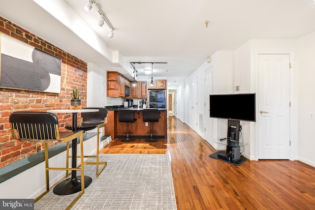 kitchen with a breakfast bar, refrigerator, hanging light fixtures, light wood-type flooring, and track lighting