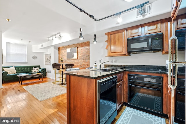 kitchen featuring sink, kitchen peninsula, light wood-type flooring, and black appliances