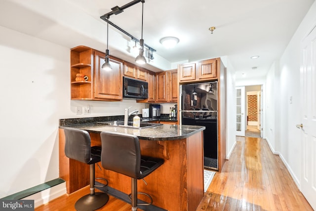 kitchen featuring a kitchen bar, decorative light fixtures, refrigerator, and kitchen peninsula