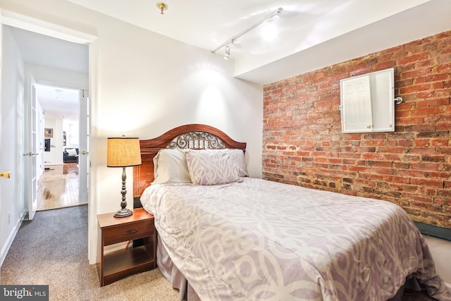 bedroom with brick wall, carpet floors, and track lighting