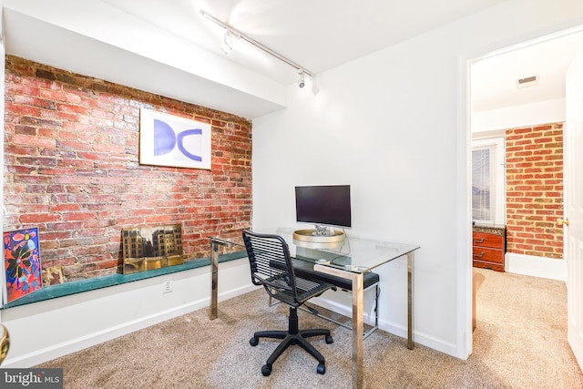 carpeted office with track lighting and brick wall