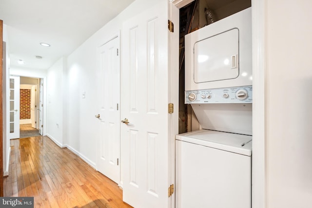 clothes washing area featuring light hardwood / wood-style flooring and stacked washer / dryer