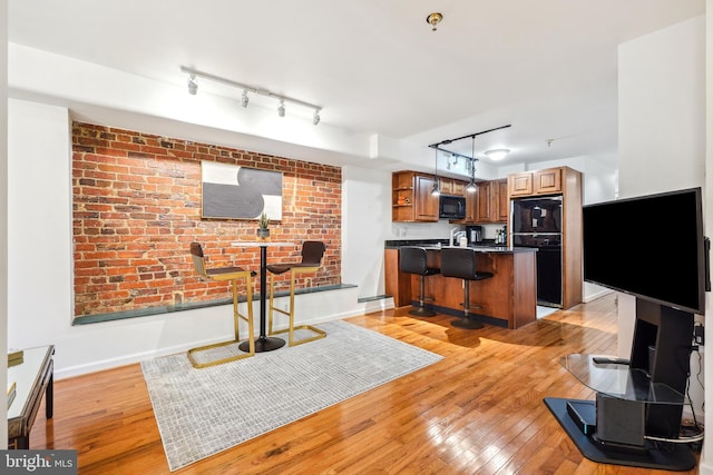 kitchen featuring a breakfast bar, decorative light fixtures, a center island, light hardwood / wood-style floors, and black appliances