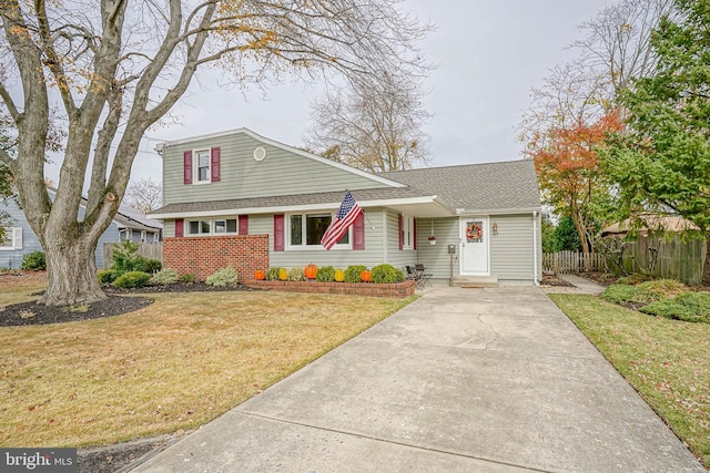 view of front of house with roof with shingles, fence, and a front lawn