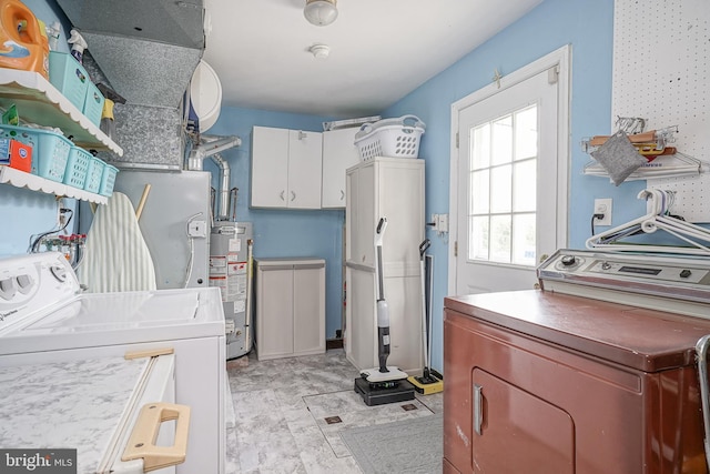 clothes washing area with separate washer and dryer, gas water heater, and cabinet space