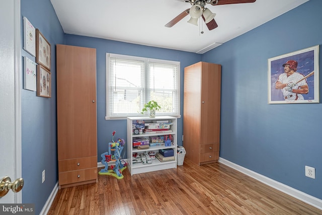 playroom with wood finished floors, a ceiling fan, and baseboards