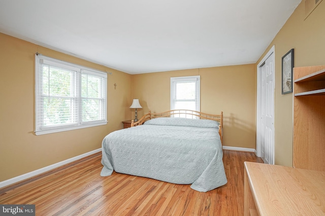 bedroom featuring a closet, wood finished floors, and baseboards