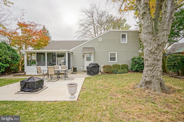 rear view of property with a fire pit, a sunroom, roof with shingles, a lawn, and a patio area