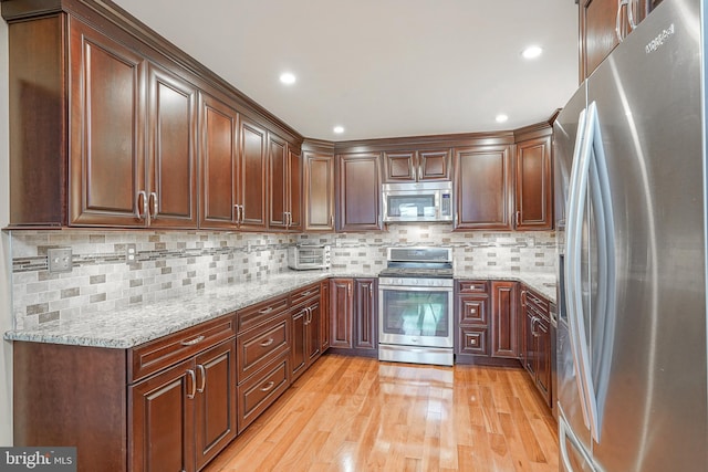 kitchen featuring light stone counters, recessed lighting, backsplash, appliances with stainless steel finishes, and light wood-style floors