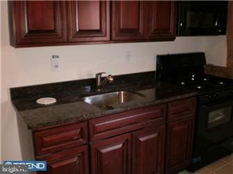 kitchen featuring dark stone counters, sink, and black appliances