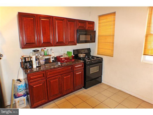 kitchen featuring sink, light tile patterned floors, black appliances, and dark stone counters