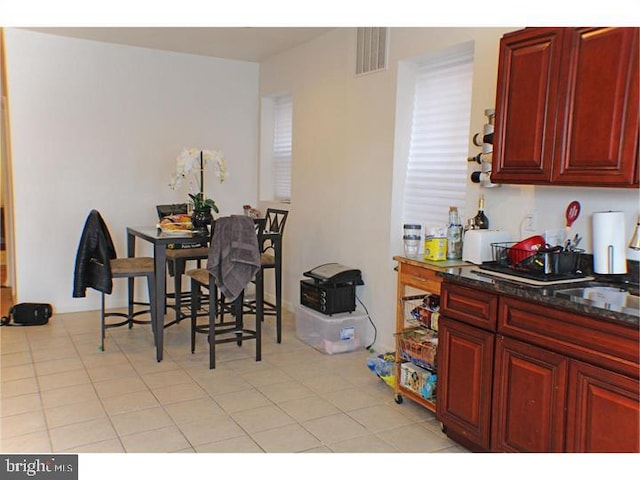 kitchen with light tile patterned floors and dark stone countertops