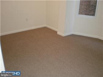 spare room featuring dark colored carpet