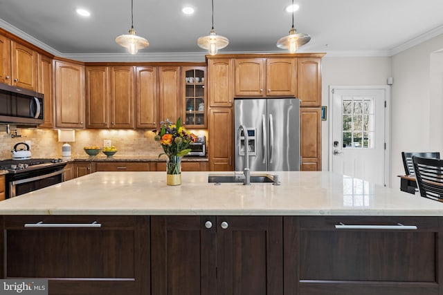 kitchen with an island with sink, ornamental molding, light stone countertops, stainless steel appliances, and backsplash