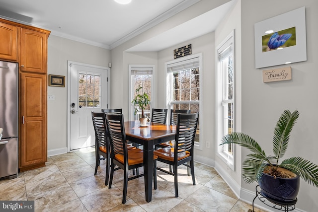 dining space with light tile patterned floors, baseboards, and crown molding