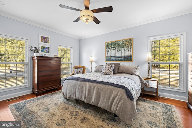 bedroom with baseboards, visible vents, ceiling fan, ornamental molding, and wood finished floors