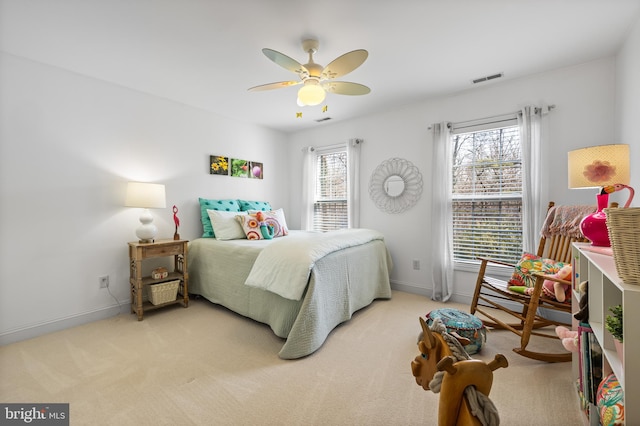 bedroom with light colored carpet, ceiling fan, baseboards, and multiple windows