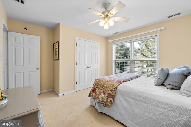 bedroom with ceiling fan, light carpet, visible vents, baseboards, and a closet