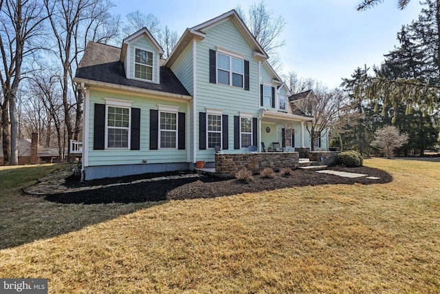 view of front facade featuring a shingled roof, a front yard, and covered porch