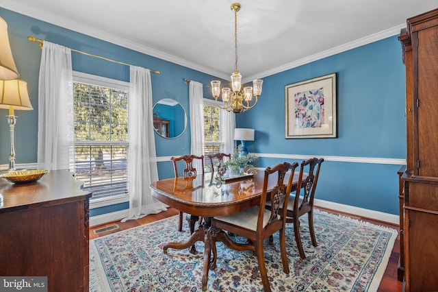 dining room featuring a chandelier, wood finished floors, visible vents, baseboards, and crown molding