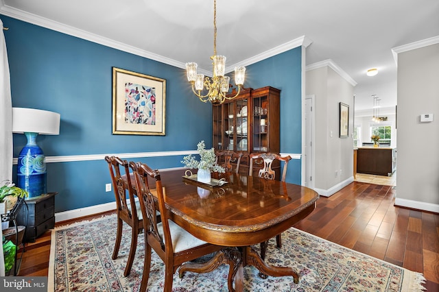 dining room featuring an inviting chandelier, crown molding, baseboards, and wood finished floors