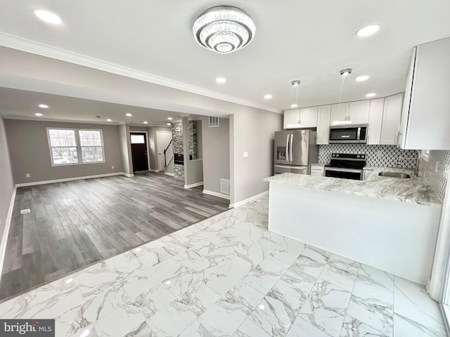 kitchen featuring crown molding, appliances with stainless steel finishes, tasteful backsplash, light stone counters, and white cabinets