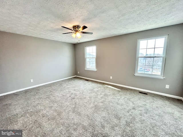 empty room featuring ceiling fan, carpet floors, and a textured ceiling