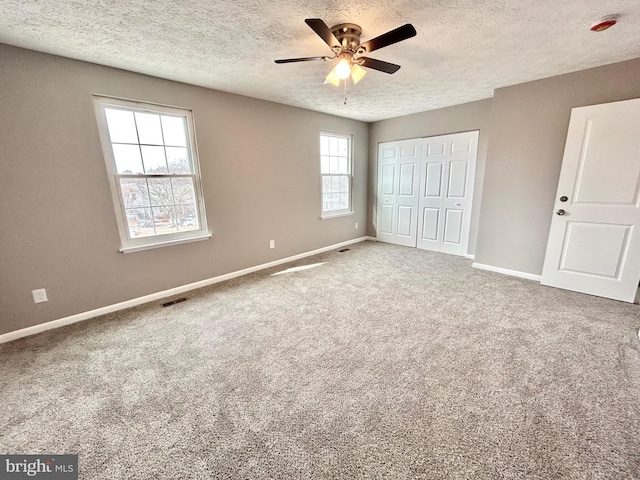 unfurnished bedroom with ceiling fan, a closet, a textured ceiling, and carpet flooring