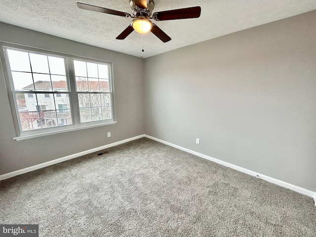 carpeted spare room featuring ceiling fan and a textured ceiling