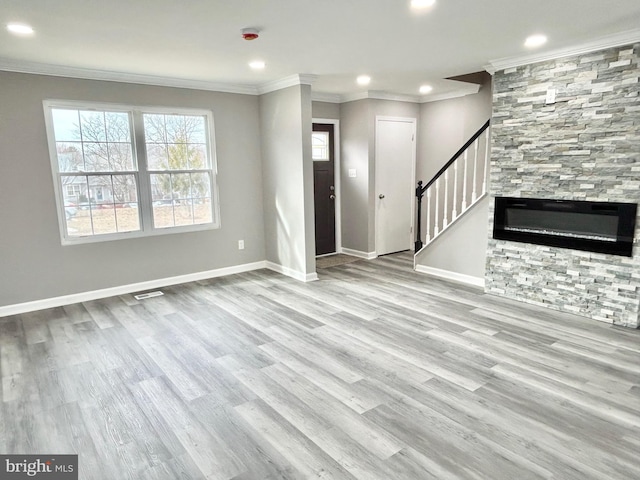 unfurnished living room featuring a fireplace, ornamental molding, and light hardwood / wood-style floors