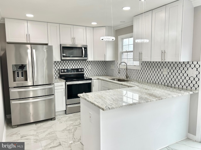 kitchen with appliances with stainless steel finishes, sink, white cabinets, and kitchen peninsula