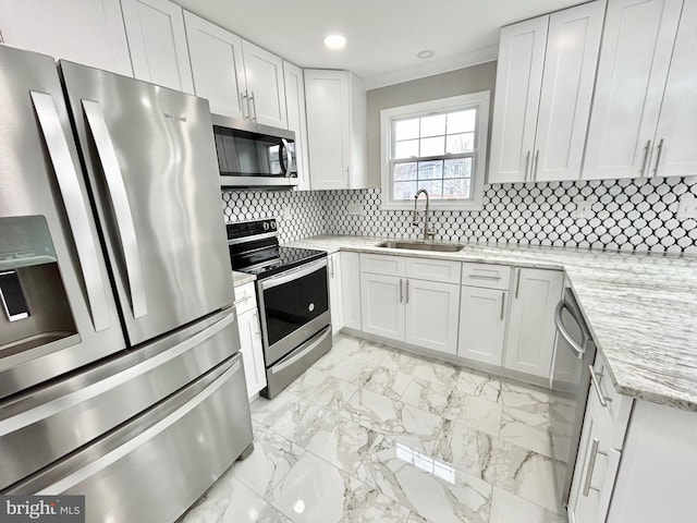 kitchen with appliances with stainless steel finishes, sink, white cabinets, decorative backsplash, and light stone countertops