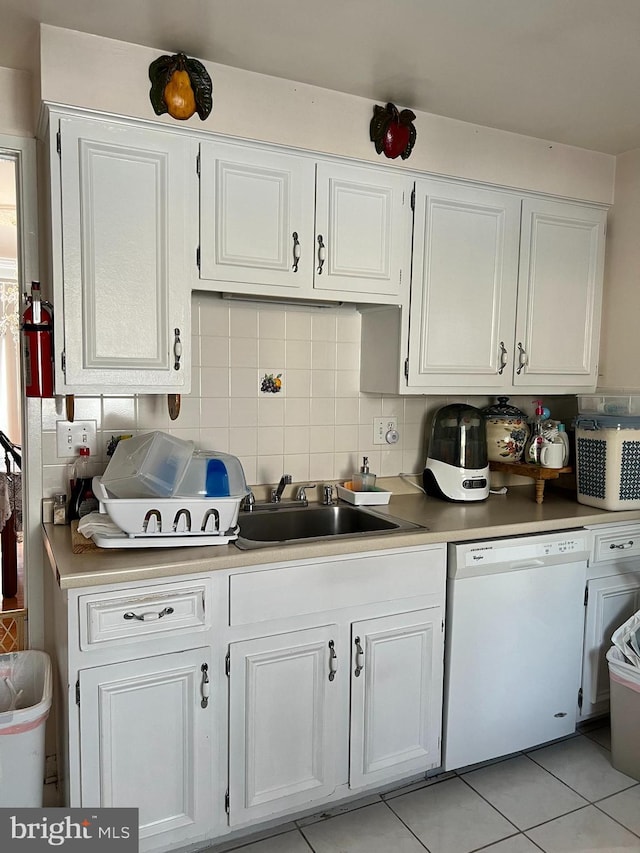 kitchen featuring sink, light tile patterned floors, dishwasher, decorative backsplash, and white cabinets