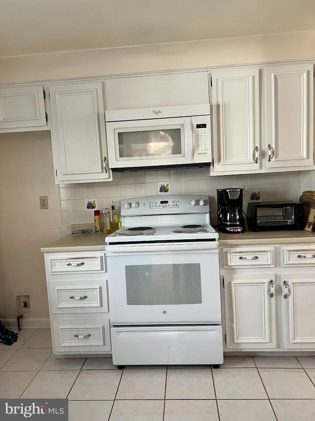 kitchen with light tile patterned flooring, white appliances, and white cabinets