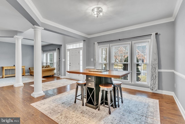 dining space featuring decorative columns, a wealth of natural light, and light hardwood / wood-style flooring