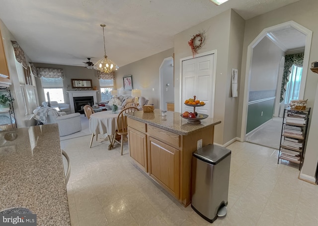 kitchen with stone counters, arched walkways, open floor plan, and light floors