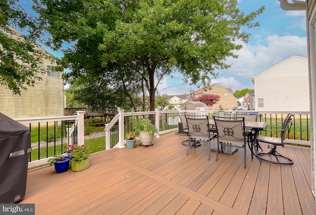 wooden terrace with outdoor dining area and area for grilling